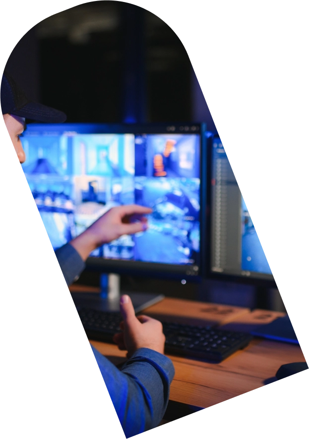 ecurity professional in a monitoring room observing CCTV screens.
